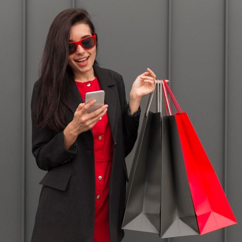 woman-holding-shopping-bags-looking-phone woman-holding-shopping-bags-looking-phone